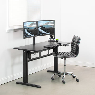Black electric desk at sitting height in a minimalist office workspace.