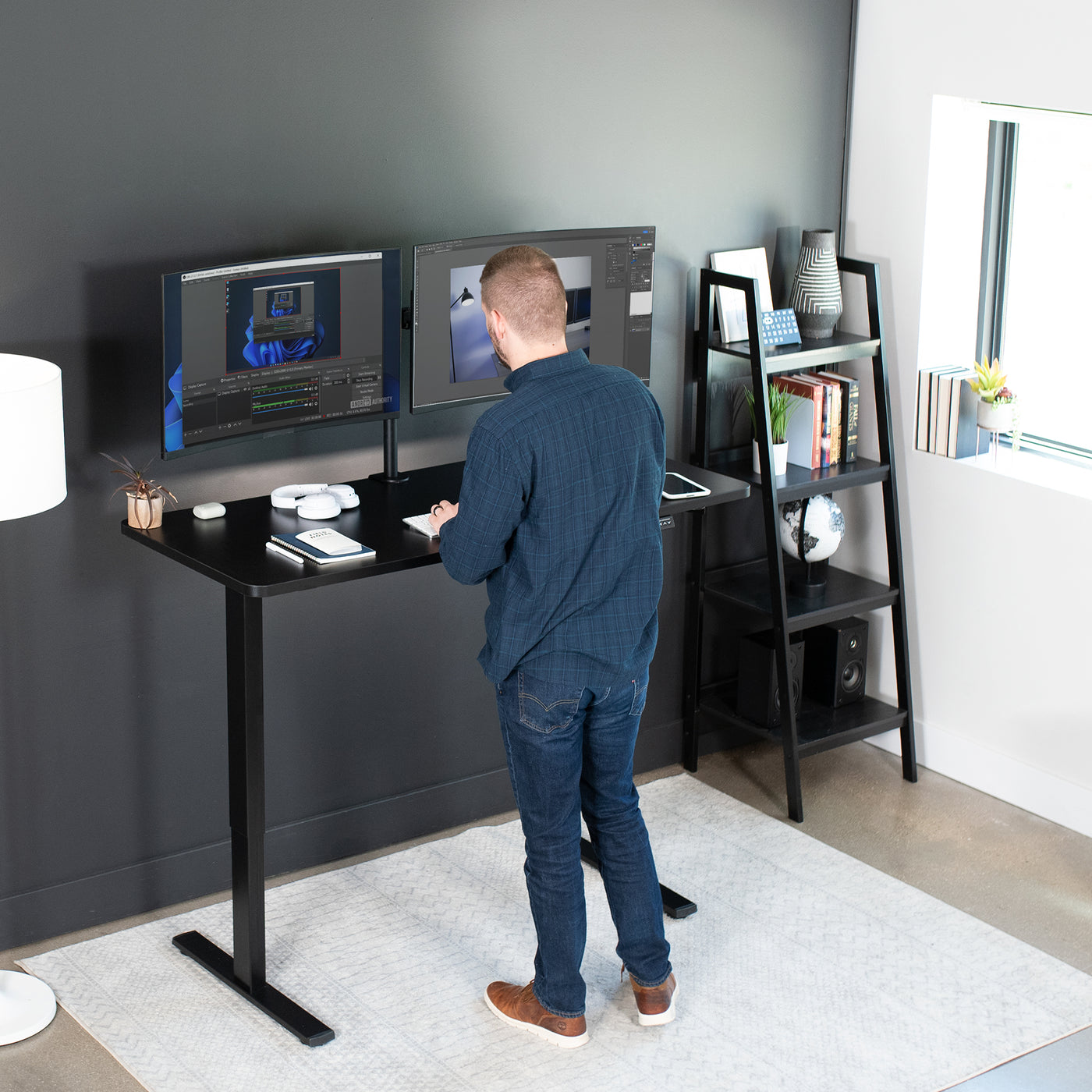 A man standing while working at an ergonomic electric desk.