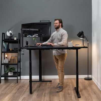 A man working at a standing desk creates an office space in the corner of a designated room.