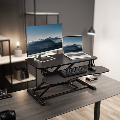 Classy modern workspace with a sit-to-stand desk  riser holding office equipment.